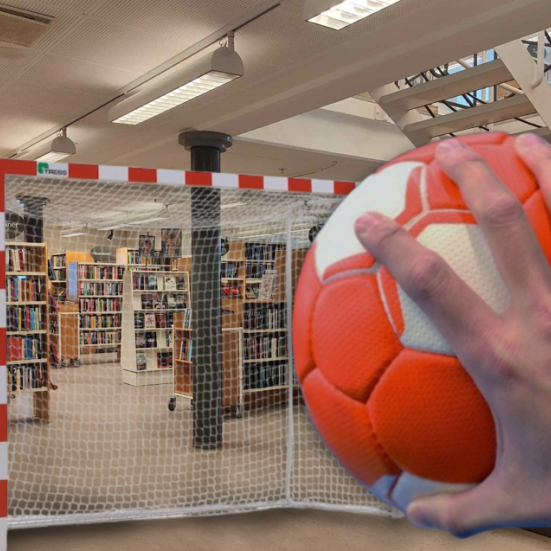 Clos-up af mandehånd med rød og hvid håndbold foran et håndboldmål, der står mellem reolerne på Brønderslev Bibliotek.