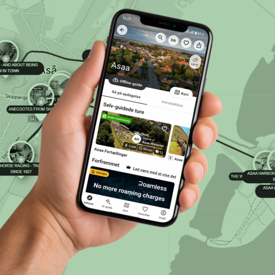 Hånd med smartphone, der viser app'en "SmartGuide" med historier om Asaa. Som baggrund ses et grøntonet kort over Asaa med hotspots.