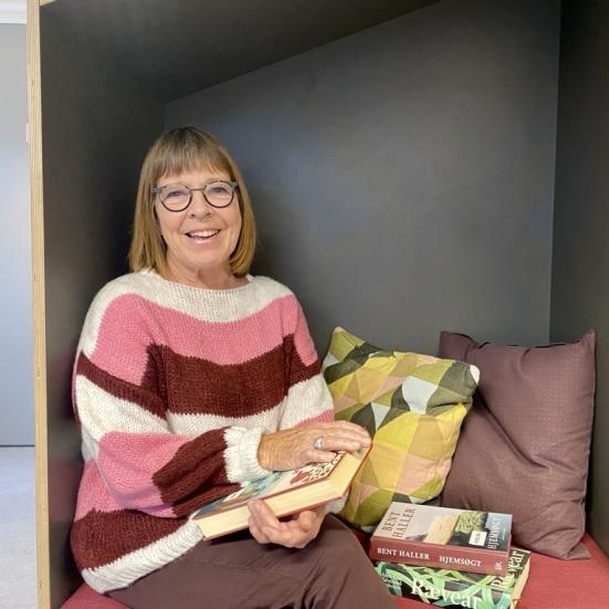Jytte Albrektsen sidder i en læsehule på biblioteket med favnen fuld af bøger