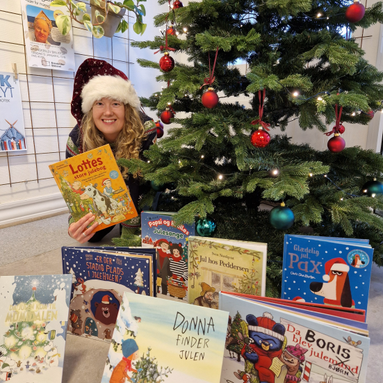 Rikke sidder ved juletræet med gode billedbøger. Det er de julebøger som nævnes i artiklen.