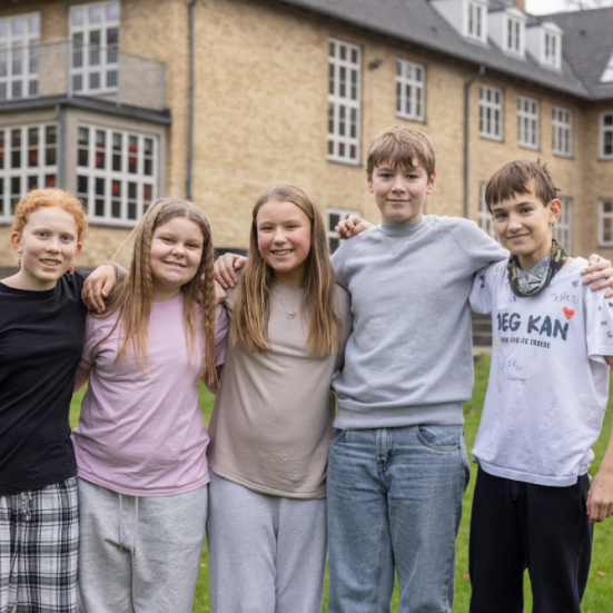 5 børn står med armene på hinandens skuldre foran Julemærkehjemmet