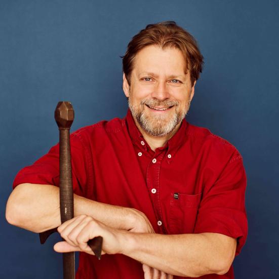 Anders Lundt Hansen sidder og læner sig til skæftet på et vikingesværd