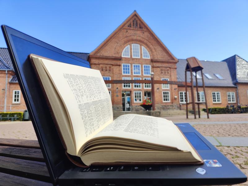 Opslået computer med opslået leksikon lagt ovenpå