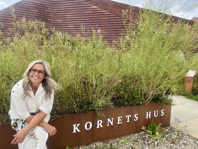 Et foto af Kornets Hus med grønne planter foran