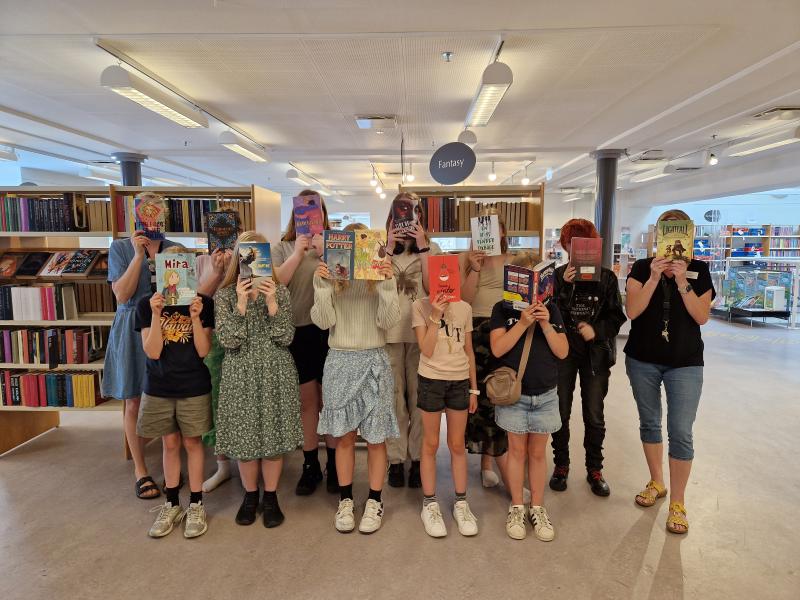 Børn der holder bøger med forsiden fremad foran deres ansigter