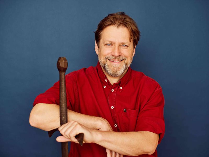 Anders Lundt Hansen sidder og læner sig til skæftet på et vikingesværd