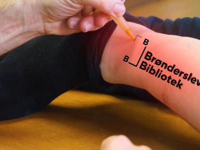Brønderslev Biblioteks logo, tatoveret på herreankel.