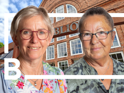 Jytte Vestergaard og Bodil Nielsen foran Brønderslev Bibliotek, indrammet af bibliotekets logo.