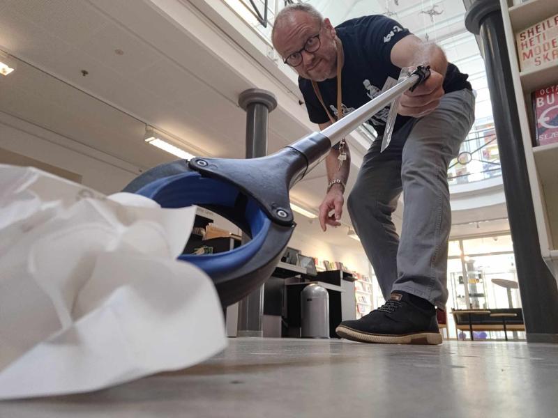 Bibliotekets formidler Hans samler affald på biblioteket med en affaldsiopsamler