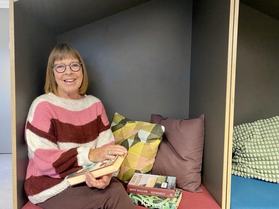 Jytte Albrektsen sidder i en læsehule på biblioteket med favnen fuld af bøger