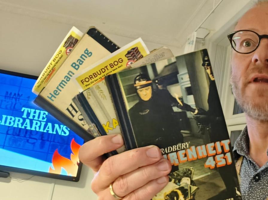 Kulturformidler Hans Wendelboe Bøcher med bl.a. Ray Bradburys "Fahrenheit 451" og andre "forbudte bøger" i hånden. I baggrunden ses plakaten til dokumentarfilmen "The Librarians".