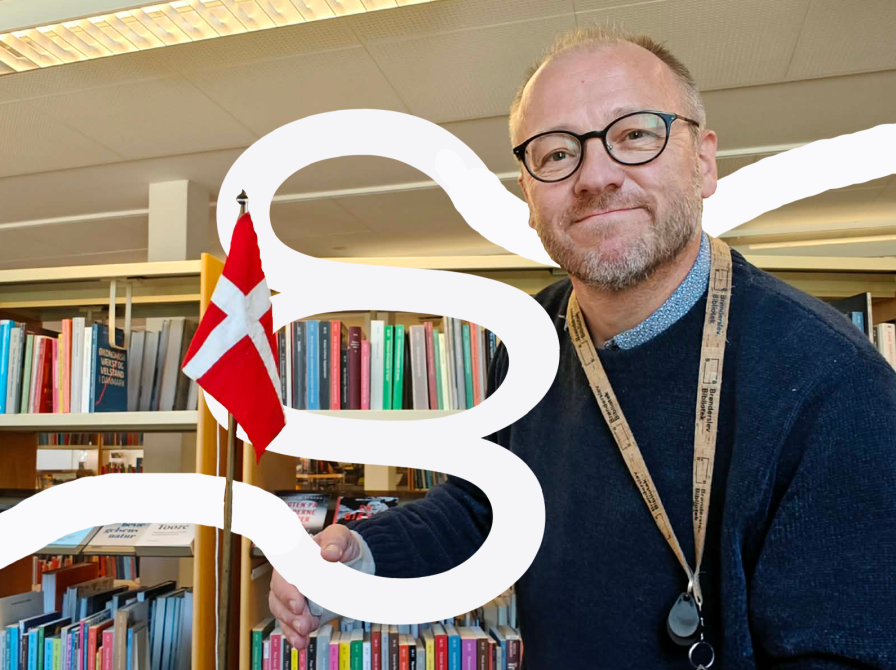 Kulturformidler Hans Wendelboe Bøcher, Dannebrogsflag, bogreoler og et stort, svungent paragraftegn.
