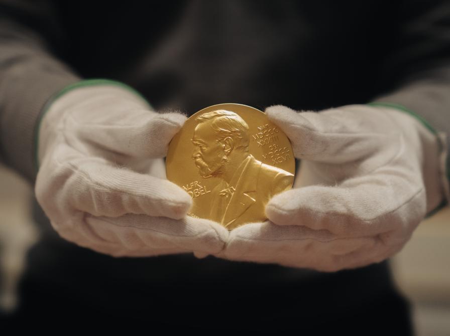 Nobelmedaljen holdes med handsker.